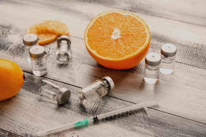 Ampoules and Serum with Vitamin C. Immunity and injection. Ampoules, syringes, tangerines and oranges on a bright yellow background. Mesotherapy and rejuvenation | Parlour at the Village in Salado, TX