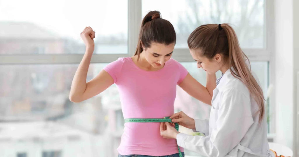 Semaglutide vs Traditional Weight Loss: What’s More Effective? 1 Female doctor measuring a young woman’s waist with a tape measure during a weight loss or health checkup in Salado, TX